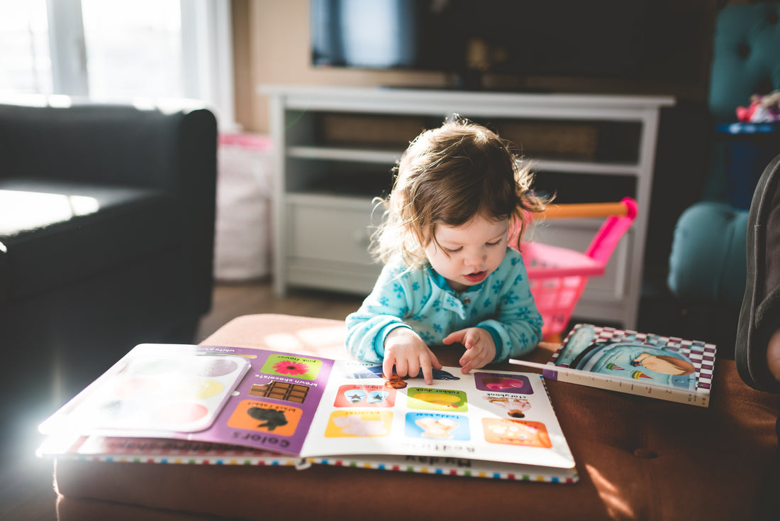 a baby is reading a children book by self