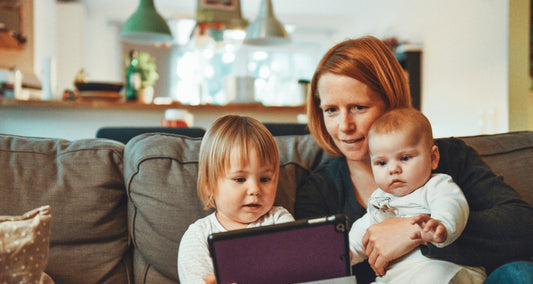 A woman with a baby is teaching a toddler